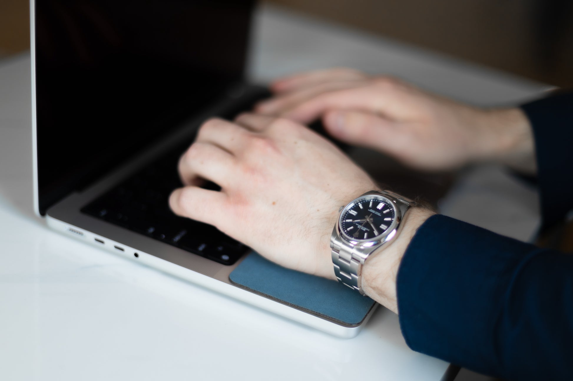 Man with luxury watch working on his Macbook while resting his hand on the WatchPad and preventing scratching.