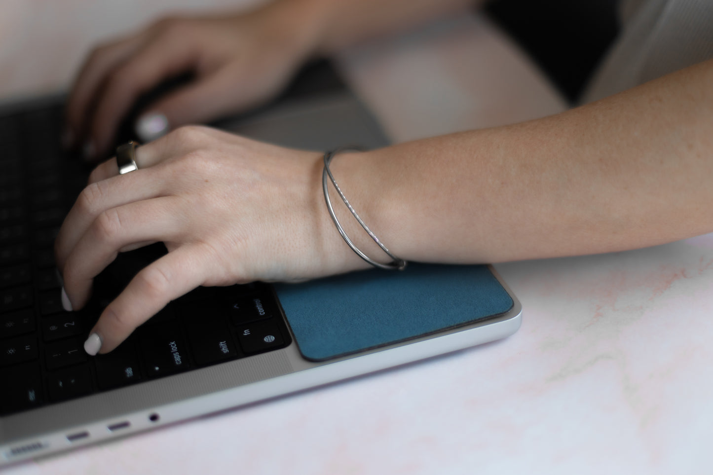 Woman with bracelet working on her computer while resting her hand on a WatchPad.